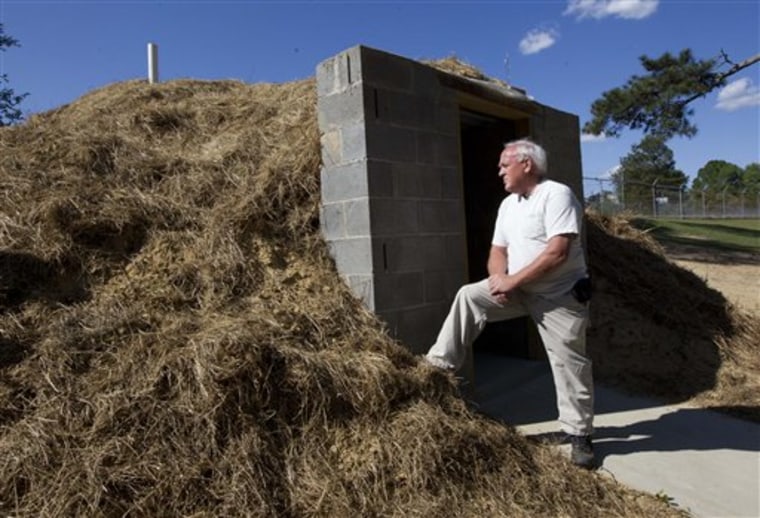 In this April 23, 2012, photo Freddie Wooten stands in front of the storm shelter he built at his own expense in Henager, Ala., following the 2011 tornado. When deadly twisters chewed through the Midwest and South in 2011, thousands of people in the killers' paths had nowhere to hide. Now many of those families are taking an unusual extra step to be ready next time: adding tornado shelters to their homes. (AP Photo/Dave Martin)